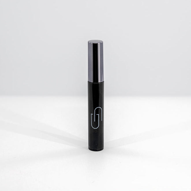 Black mascara tube with silver cap on a white background